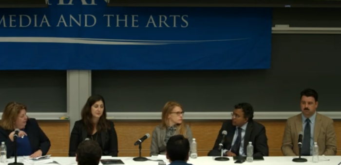 Five individuals seat at a conference table in discussion 