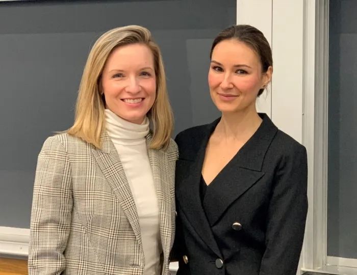 Anne Bracegirdle and Angela Redai dressed professionally are smiling for a picture while standing in front of a board