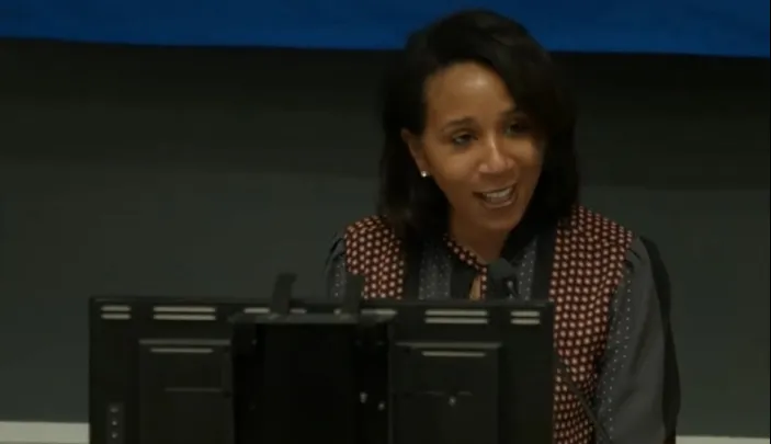 Karyn Temple smiles while seated behind computer monitor.  