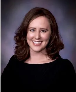 Caitlin McGrail headshot.  She is smiling and wears a textured black blouse.
