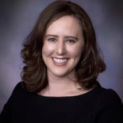 Portrait photo of Caite McGrail, a white woman with brown hair and blue eyes in a black top